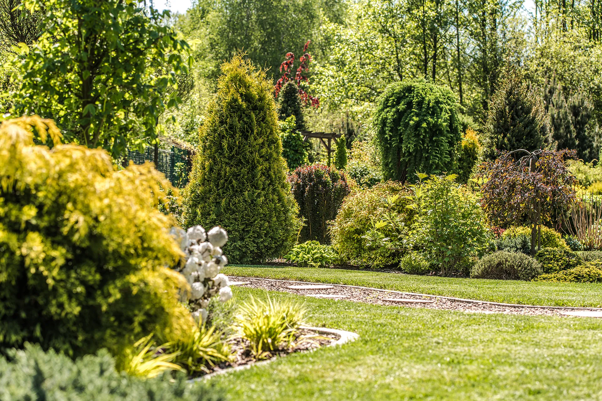 MASO Gartengestaltung Sauber geschnittene Hecke entlang eines Gartenzauns